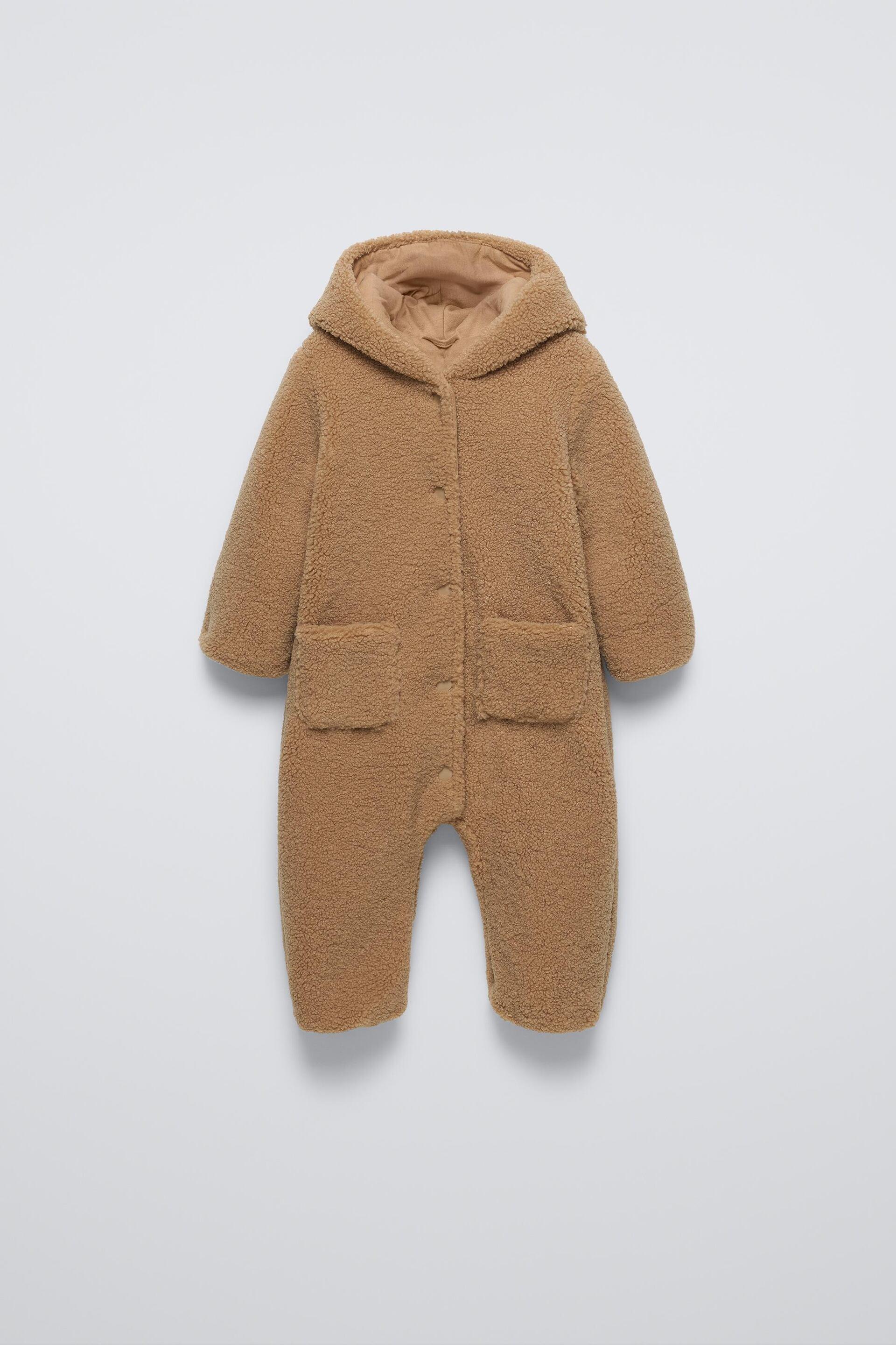 Faux shearling bodysuit with hood and long sleeves. Snap button closure and front patch pockets.Interior lining. by ZARA