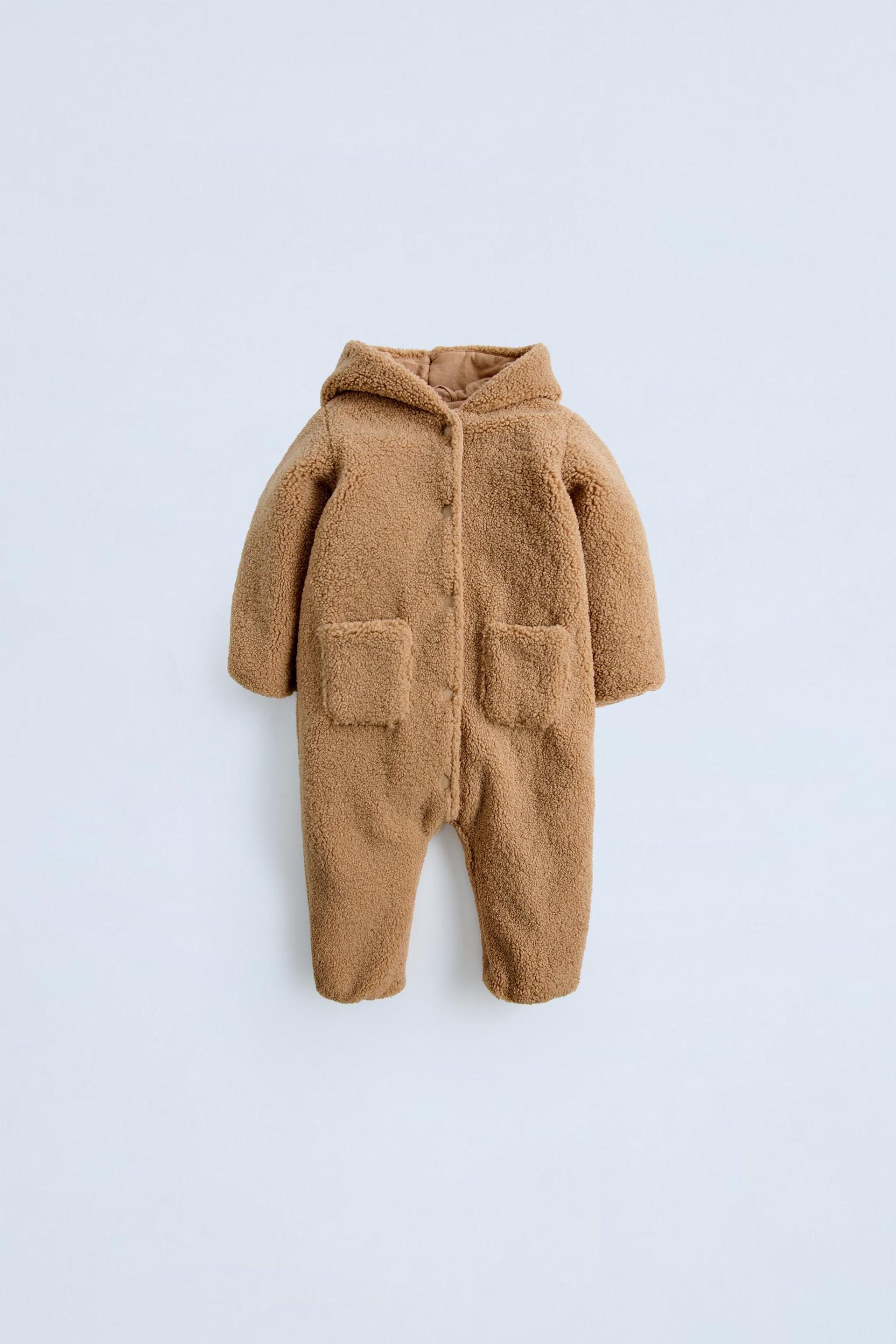 Faux shearling bodysuit with hood and long sleeves. Snap button closure and front patch pockets.Interior lining. by ZARA